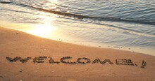 Welcome Sign On The Shore. A View Of The Word Welcome On The Wet Sand On The Beach.