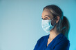 © PoppyPix - European woman nurse in her 30s observing surgery while wearing facial mask that covers her mouth and nose. High quality photo