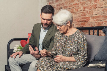 caucasian relatives with age difference comparing printed photographs to the ones taken with smartphone. High quality photo