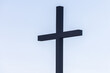 dark silhouetted cross on pale blue sky