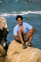 A man sitting on a rock on the beach, at the beach, Margarita Island, Venezuela.