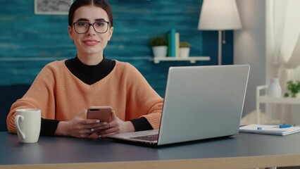 Wall Mural - Portrait of woman working on smartphone to learn for exam, browsing internet to take notes on school lecture. University student using mobile phone and laptop at home, remote education.