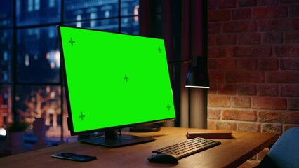 Fototapete - Desktop Computer Monitor Standing on a Table with a Green Screen Chromakey Mock Up Display. Cozy Empty Loft Apartment with Big Window with a Lamp, Notebook and Smartphone on the Table. Arc Shot.