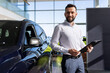 © Ivan Traimak - insurance company employee next to a new car in a car dealership center