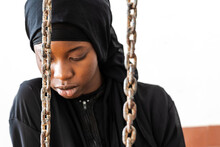 Scared Young African Girl Behind Chains, Symbol Of Domestic Abuse, Child Or Forced Marriage, Gender Disequality