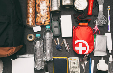 emergency backpack equipment organized on the table. documents, water,food, first aid kit and anothe