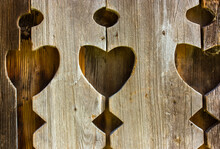 Outhouse Heart Detail On Carved Wooden Wall, Fence. Hearts On Rustic Old Wooden Board, Desk. Cut Holes In The Shape Of A Hearts. Wood Carving. Decorating The Exterior Of A House, Retro Building.