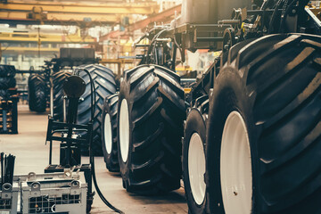 Wall Mural - Conveyor line for production and assembly of large industrial machines, tractors or combines. Big rubber tires in factory.