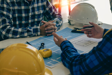 2 construction site engineers On-site engineering objects work with interactive partners and behind the scenes pointing on blueprints and using a laptop to draw office building design projects.