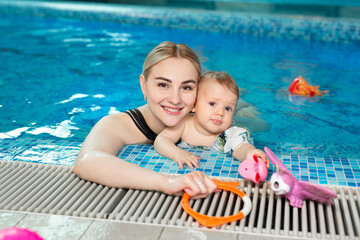 Wall Mural - Young mother and her baby daughter play in the pool.