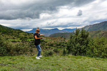 A girl on the background of the village of Kurib in the Caucasus mountains, on top of a cliff. Dagestan Russia June 2021