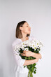 © arthurhidden - Young beautiful cute sweet lovely smiling woman with hold a bouquet of white fresh flowers on white wall background
