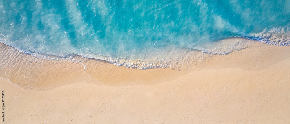 Summer seascape beautiful waves, blue sea water in sunny day. Top view from drone. Sea aerial view, amazing tropical nature background. Beautiful bright sea with waves splashing and beach sand concept