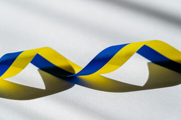 Wall Mural - Blue and yellow ribbon on white background with shadow.