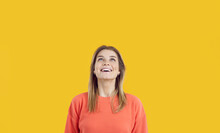 Smiling Young Caucasian Girl Isolated On Yellow Studio Background Look Up Think Of Offer Or Promotion. Happy Millennial Woman Amazed Excited With Good Sale Deal Or Discount. Copy Space, Ad.