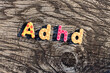 Letters ADHD written on colorful toy text on wooden surface. Attention deficit hyperactivity disorder concept.