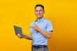 © Bangun Stock Photo - Portrait of cheerful handsome Asian man in glasses pointing finget at laptop,showing something online isolated on yellow background. businessman and entrepreneur concept