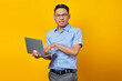 © Bangun Stock Photo - Smiling young asian man Asian in glasses using laptop isolated on yellow background. businessman and entrepreneur concept