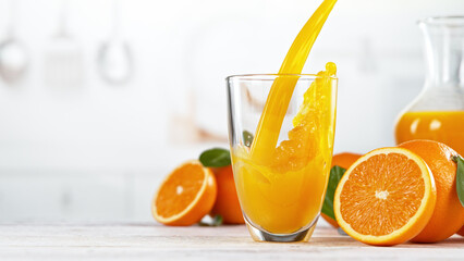 Orange juice pouring into glass. Fresh orange juice with oranges fruit in kitchen.