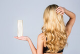 Woman long hair. Woman hold bottle shampoo and conditioner. Woman holding shampoo bottle. Beautiful blonde girl with a bottle of shampoos in hands. Girl with shiny and long hair
