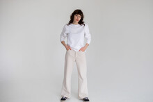 Young Woman With Curly Hair In A White Long Sleeve T-shirt Stands On A White Background. Mock-up.