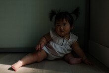 Asian Baby Sitting In Deep Shadows
