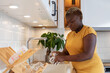 © Anna Berkut/Stocksy - black woman washing dishes in the kitchen at home