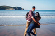 © Igor Kardasov/Stocksy - Couple having fun on ocean beach in cold weather