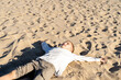 © Albert Martinez/Stocksy - Cheerful kid lying on sandy seashore in sunlight