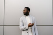 © Ezequiel Giménez/Stocksy - African American man with smartphone near modern wall