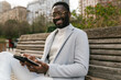 © Ezequiel Giménez/Stocksy - Smiling black man using tablet in park