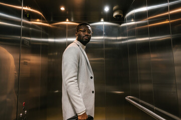 Black guy standing in metal elevator