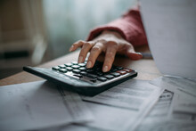 Close-up Of Woman's Hands With Calculator And Utility Bills. The Concept Of Rising Prices For Heating, Gas, Electricity.