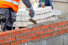 Bricklayer Laying Bricks On Mortar On New Residential House Construction