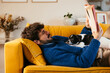 © BONNINSTUDIO/Stocksy - Dog resting on owner reading book on couch