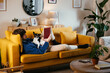 © BONNINSTUDIO/Stocksy - Man with dog reading book on sofa
