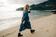 © Olga Moreira/Stocksy - Woman walking along the sea during sunset