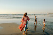© Erin Brant/Stocksy - Mom and girls on beach watching swimmers