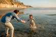 © Erin Brant/Stocksy - Young girl running in ocean toward dad's arms