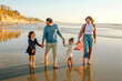 © Erin Brant/Stocksy - Mom, dad and girls walking on beach
