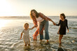© Erin Brant/Stocksy - Mom and girls wading in ocean at sunset