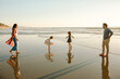 © Erin Brant/Stocksy - Parents watch daughters dance on beach at sunset