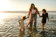 © Erin Brant/Stocksy - Mom and daughters wading in ocean surf