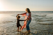 © Erin Brant/Stocksy - Mother and daughter dancing in surf at sunset