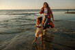 © Erin Brant/Stocksy - Laughing mom chasing daughter on beach