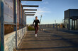 © Javier Díez/Stocksy - Woman jogger running along bridge in sunlight
