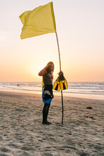 Black Lifeguard With Flag And Flippers On Seashore