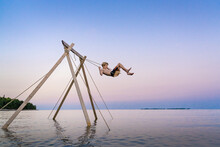 Boy On Lake Swing During Luxury Summer Vacation