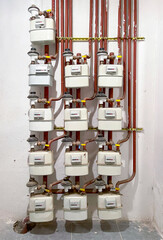 group of gas counters, gas meter room of a residential building, gas meter consumption device with red pipes, vertical