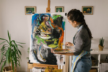 Female Art Student Painting On Canvas In Home Studio
